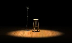 Microphone stand and wooden stool under a spotlight on a stage