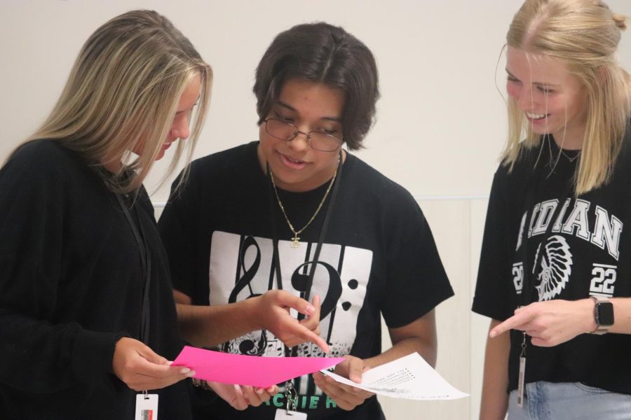 Junior Carli Reames, sophomore Eric Longoria, and junior Emma Cummings look at the information posted about the culture club and the debate club